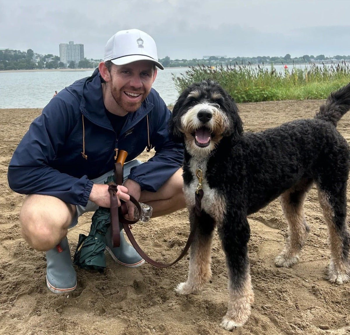 Bobby, founder of DASH, crouching on a beach with his dog